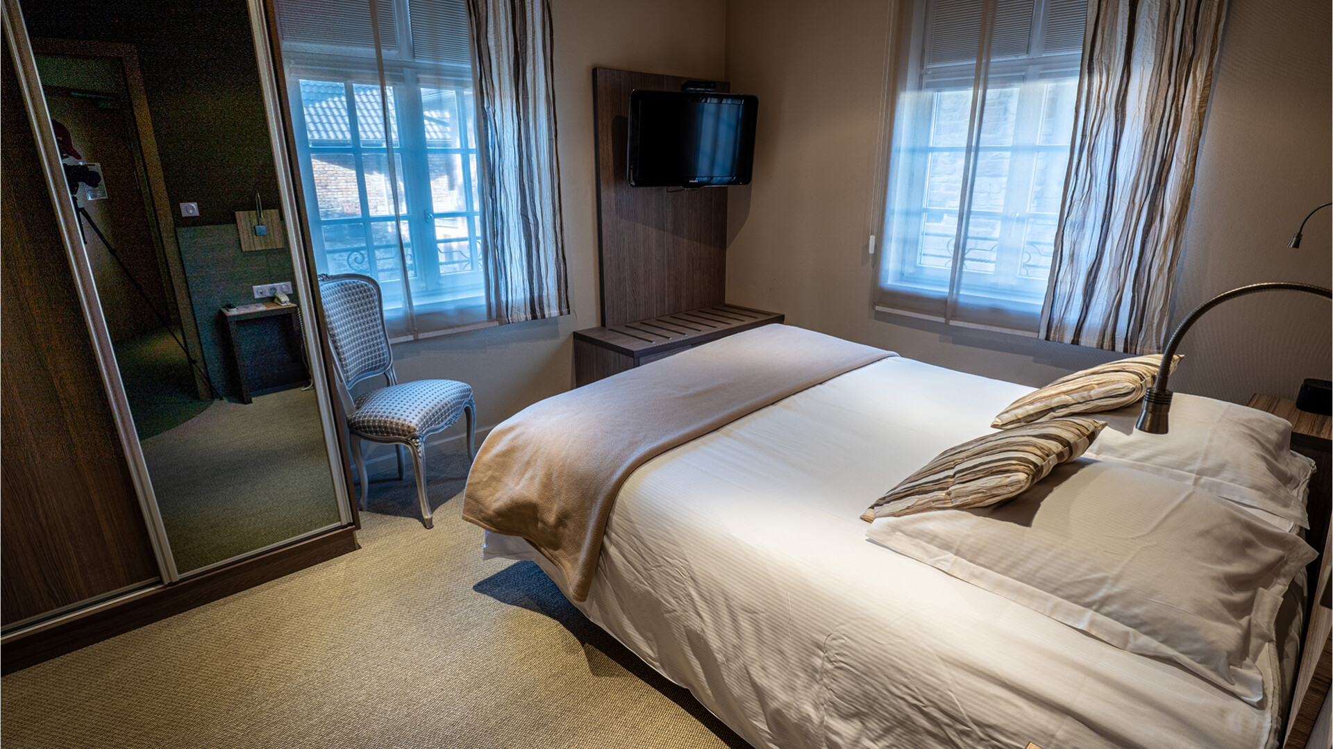 Chambre avec lit double, TV et miroir.