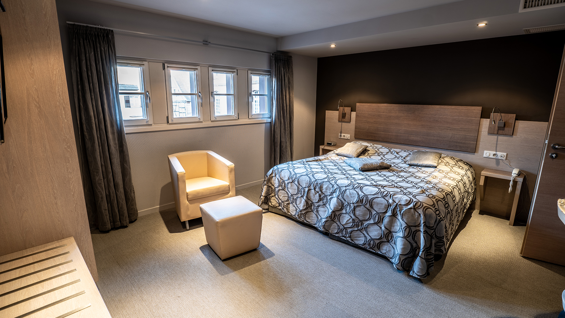 Vue générale de la chambre 35 avec lit double, fauteuil beige et fenêtres lumineuses