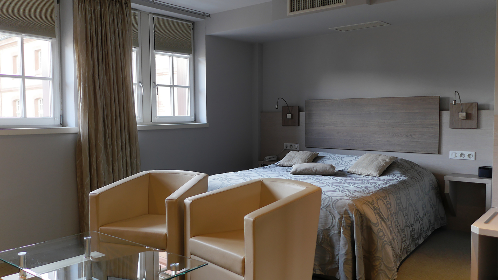 Chambre 36 avec lit double et espace salon composé de fauteuils beiges