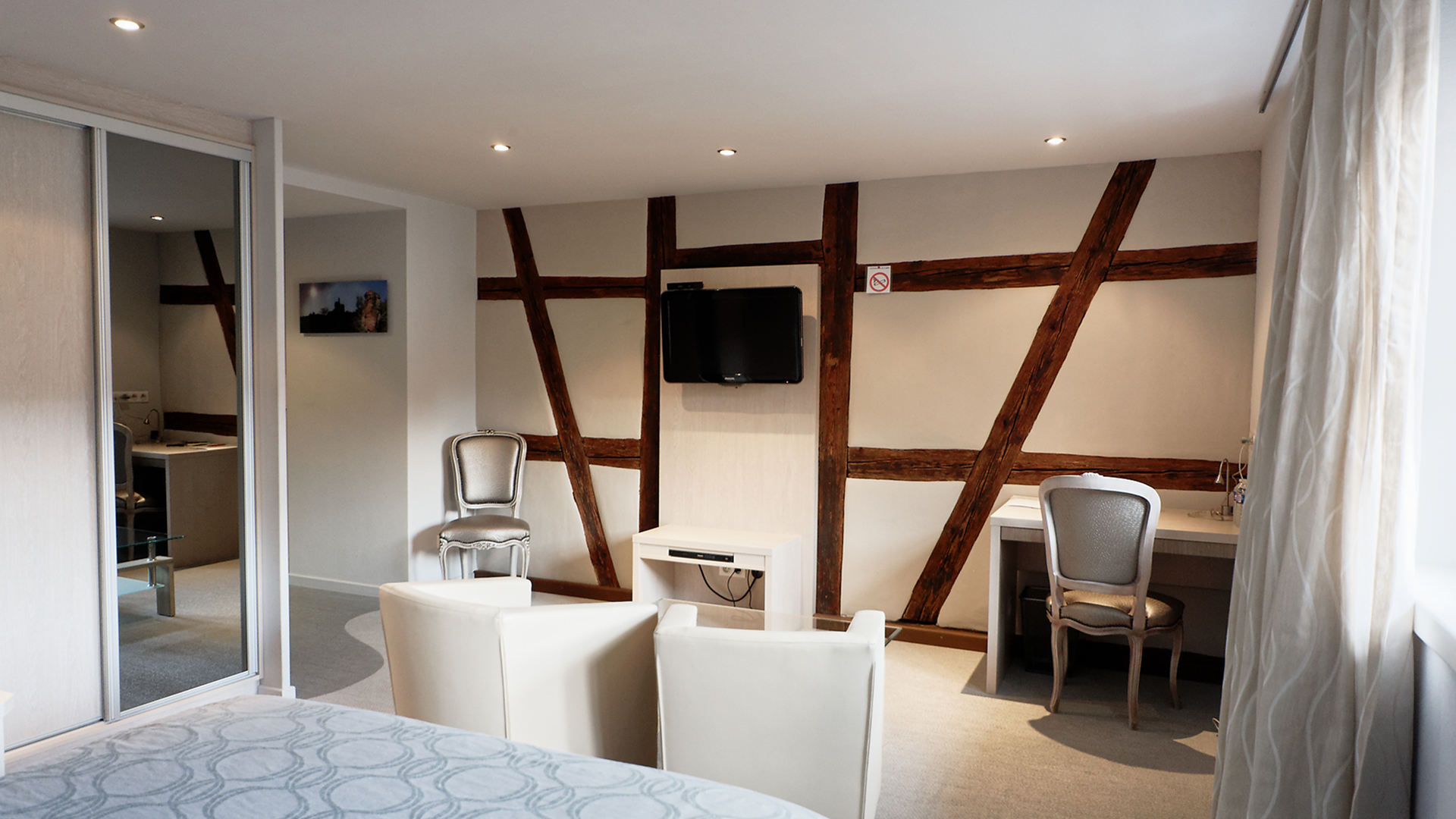 Coin salon avec télévision murale, fauteuils confortables et coin bureau