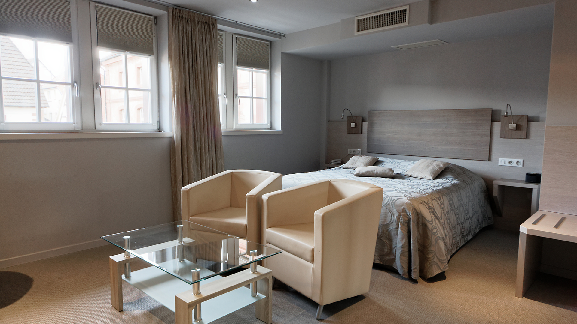 Coin salon lumineux avec fauteuils beiges et table basse en verre