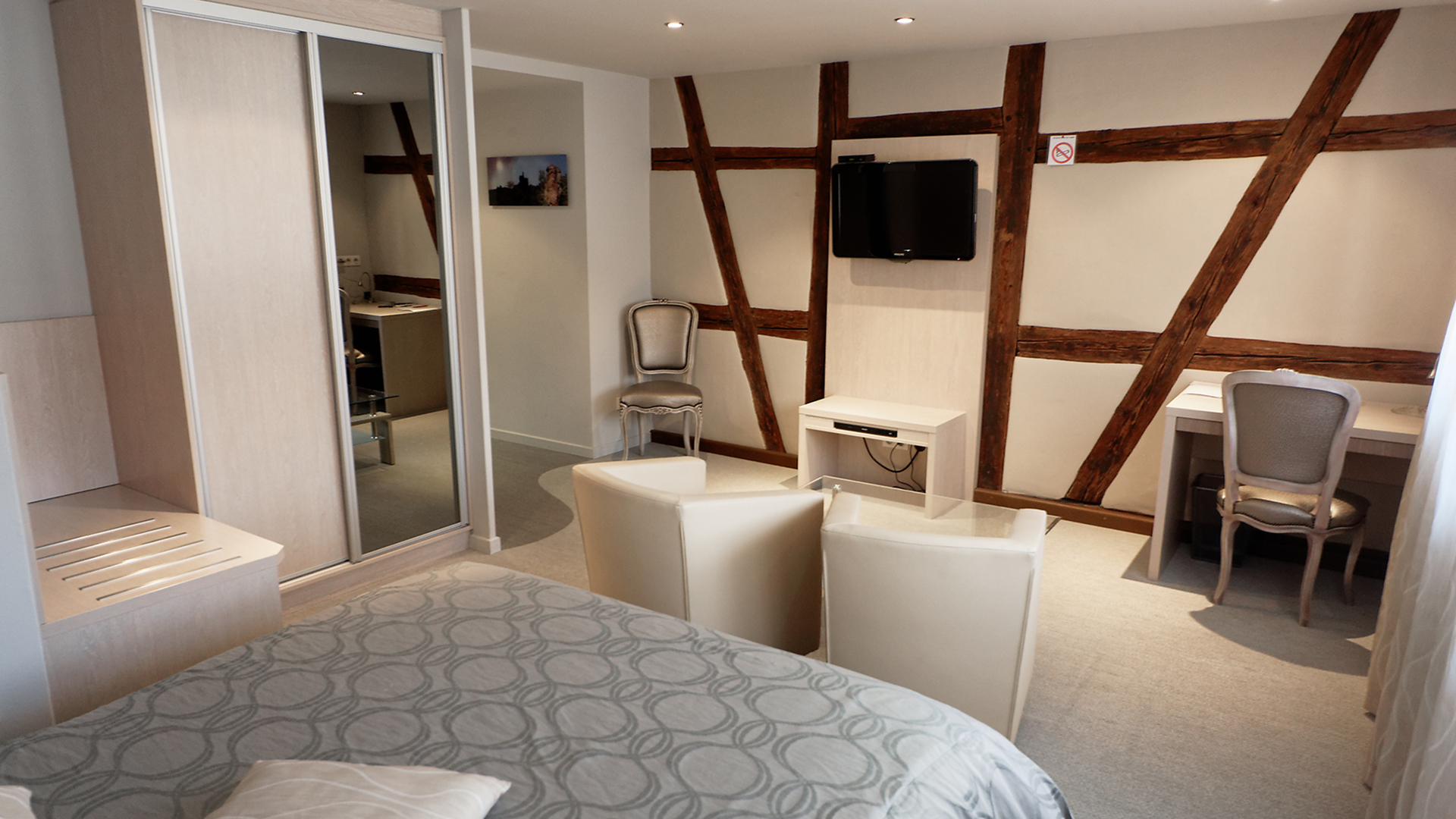 Vue générale avec lit double, espace salon et dressing avec miroir