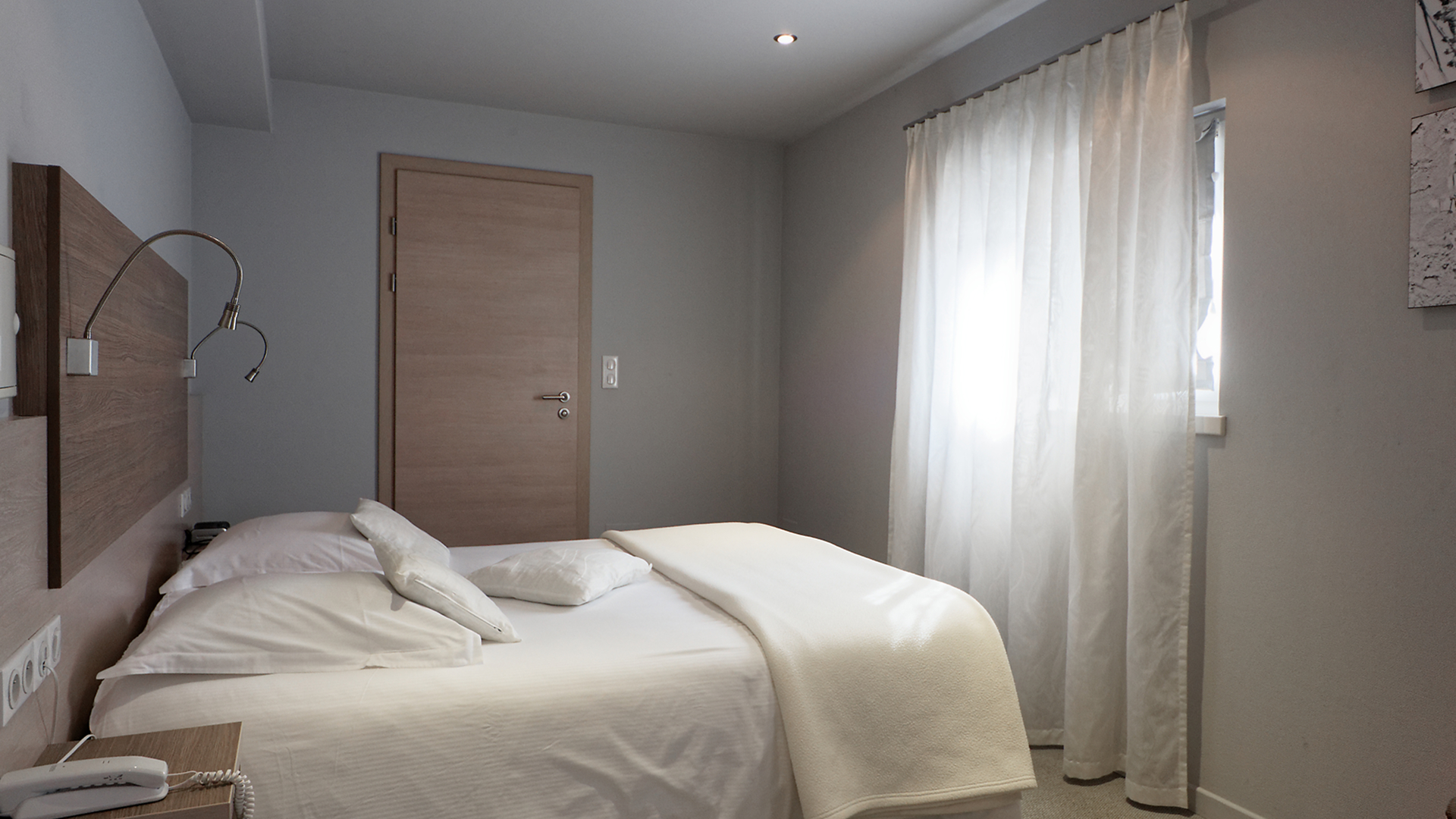 Chambre lumineuse avec lit double confortable et fenêtre avec rideaux blancs