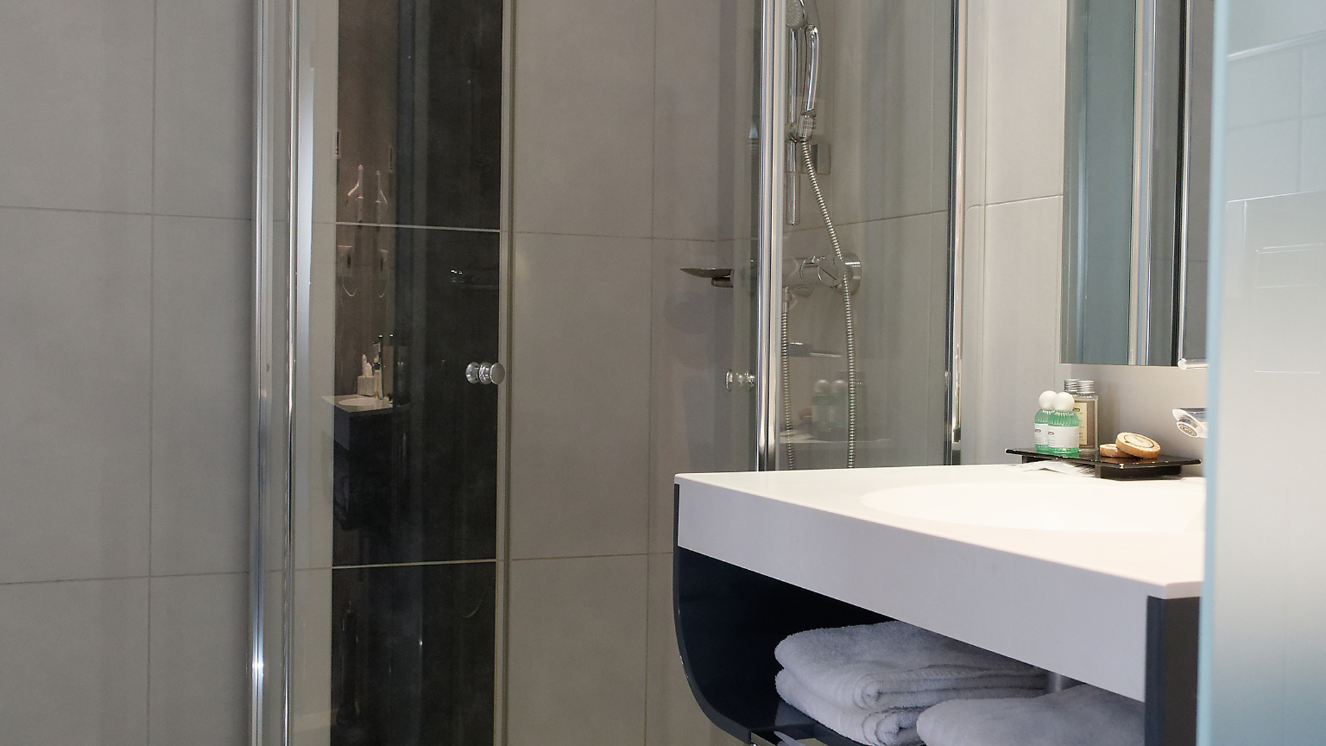 Salle de bains élégante avec grande douche vitrée et équipements pratiques