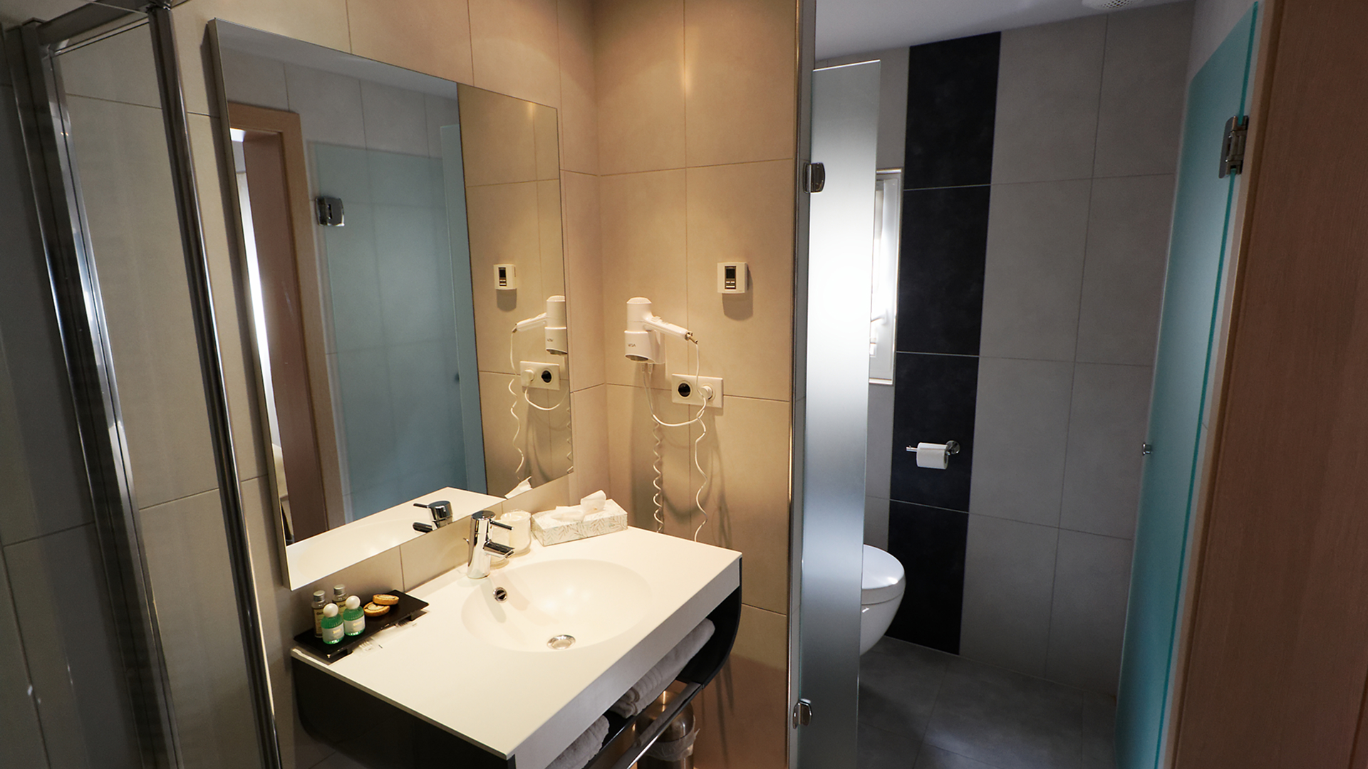 Salle de bains avec lavabo moderne, miroir éclairé et douche séparée