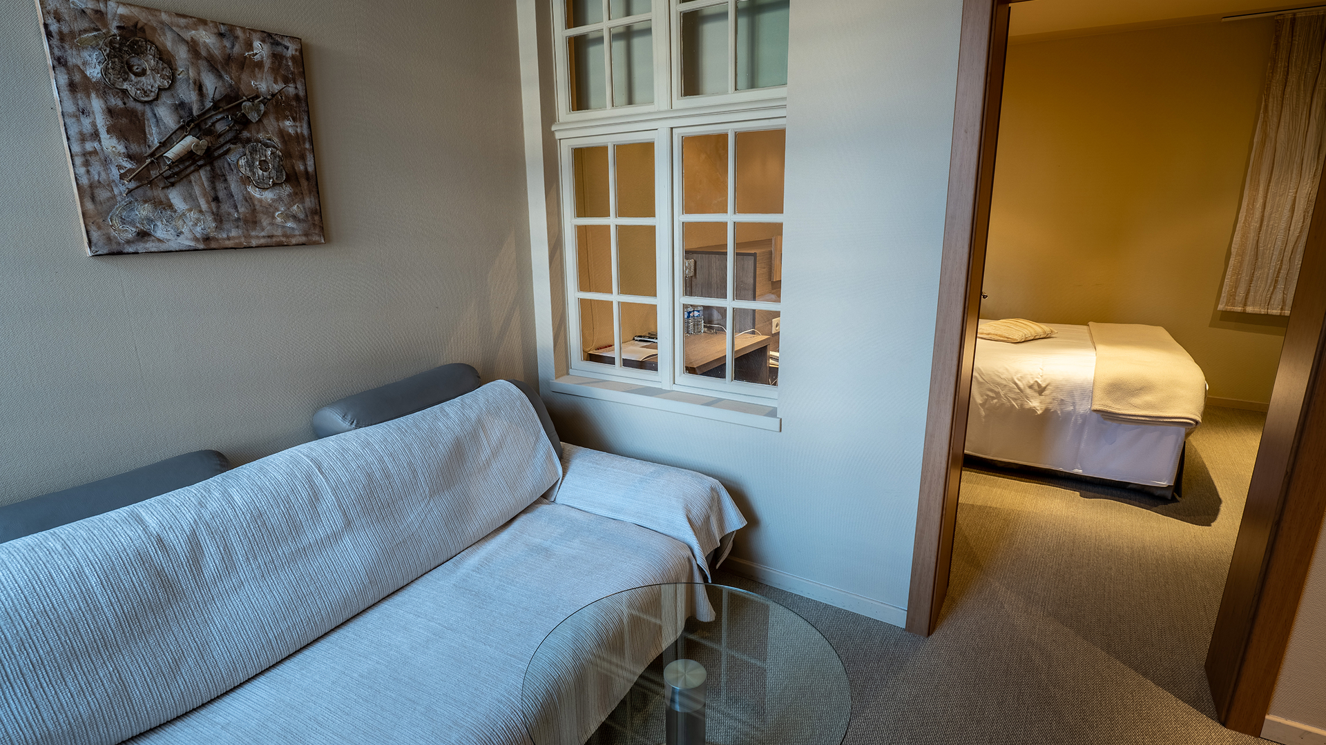 Salon privé avec canapé et vue vers la chambre.