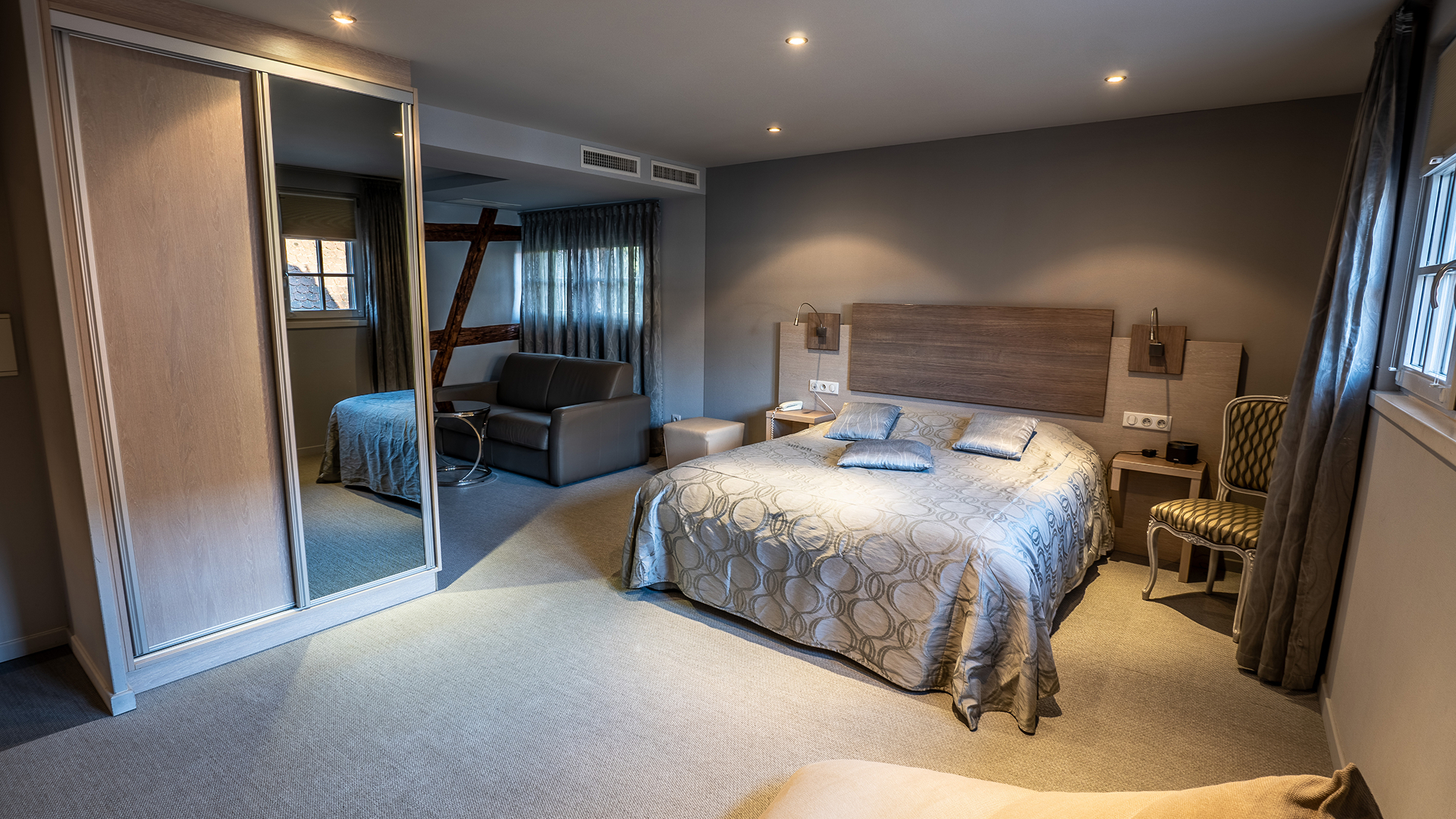 Vue depuis l’entrée montrant le lit double, le coin salon et l'armoire miroir