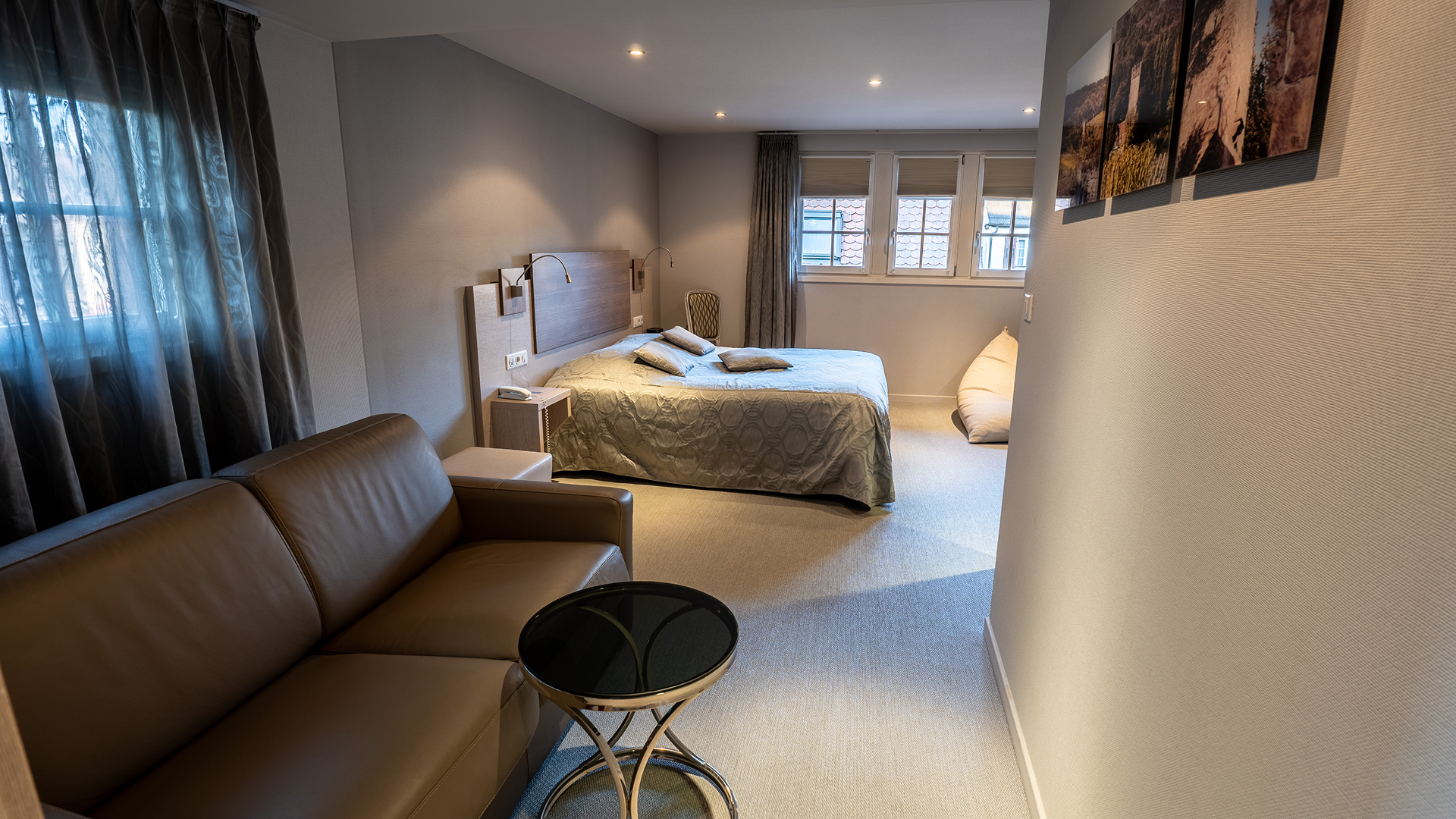 Coin salon avec canapé en cuir marron, table basse et vue vers le lit