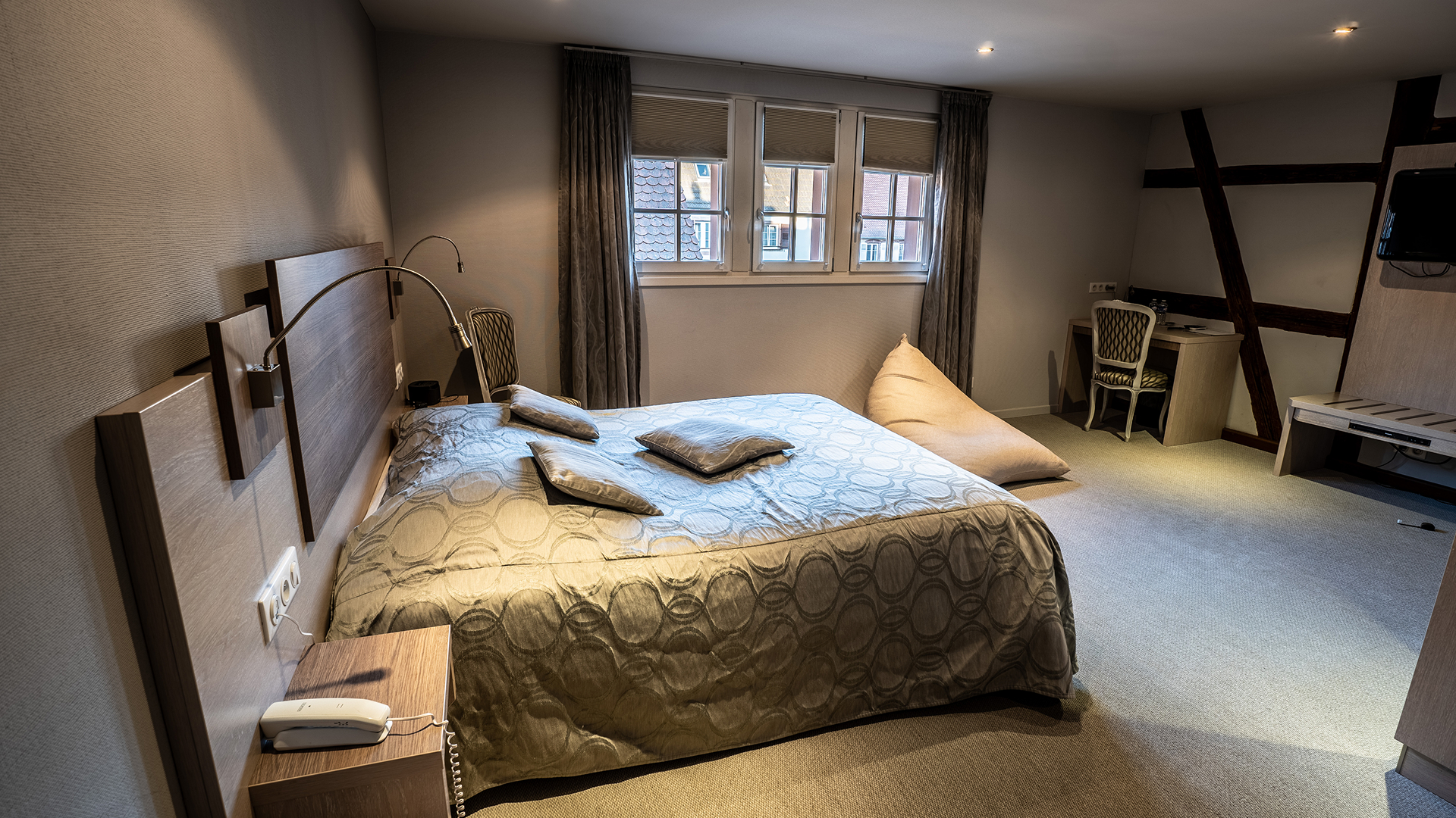 Vue latérale de la chambre montrant le lit double, coin bureau et télévision